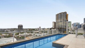 A rooftop pool with a city view, surrounded by modern buildings. - Central Apartment with Rooftop Pool & Views (South Brisbane)