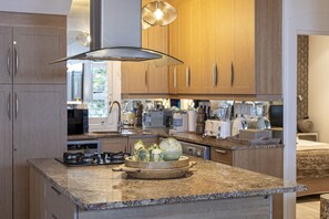 Uma cozinha moderna com bancadas de granito, armários de madeira e eletrodomésticos de aço inoxidável.
