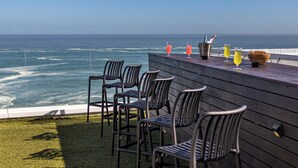 A terrace with four chairs and a wooden table, overlooking the ocean. - Clifton Sea View Duo Penthouse (Cape Town)