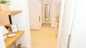Un couloir avec des étagères en bois, un miroir et un réfrigérateur.