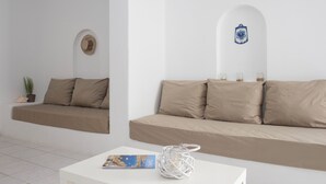 A minimalist living room with a sofa and a coffee table, a potted plant, and a decorative wall piece. - Artemis | 1 Bedroom Apartment with partial mountaView and Patio, Cleopatra Home (Paros)