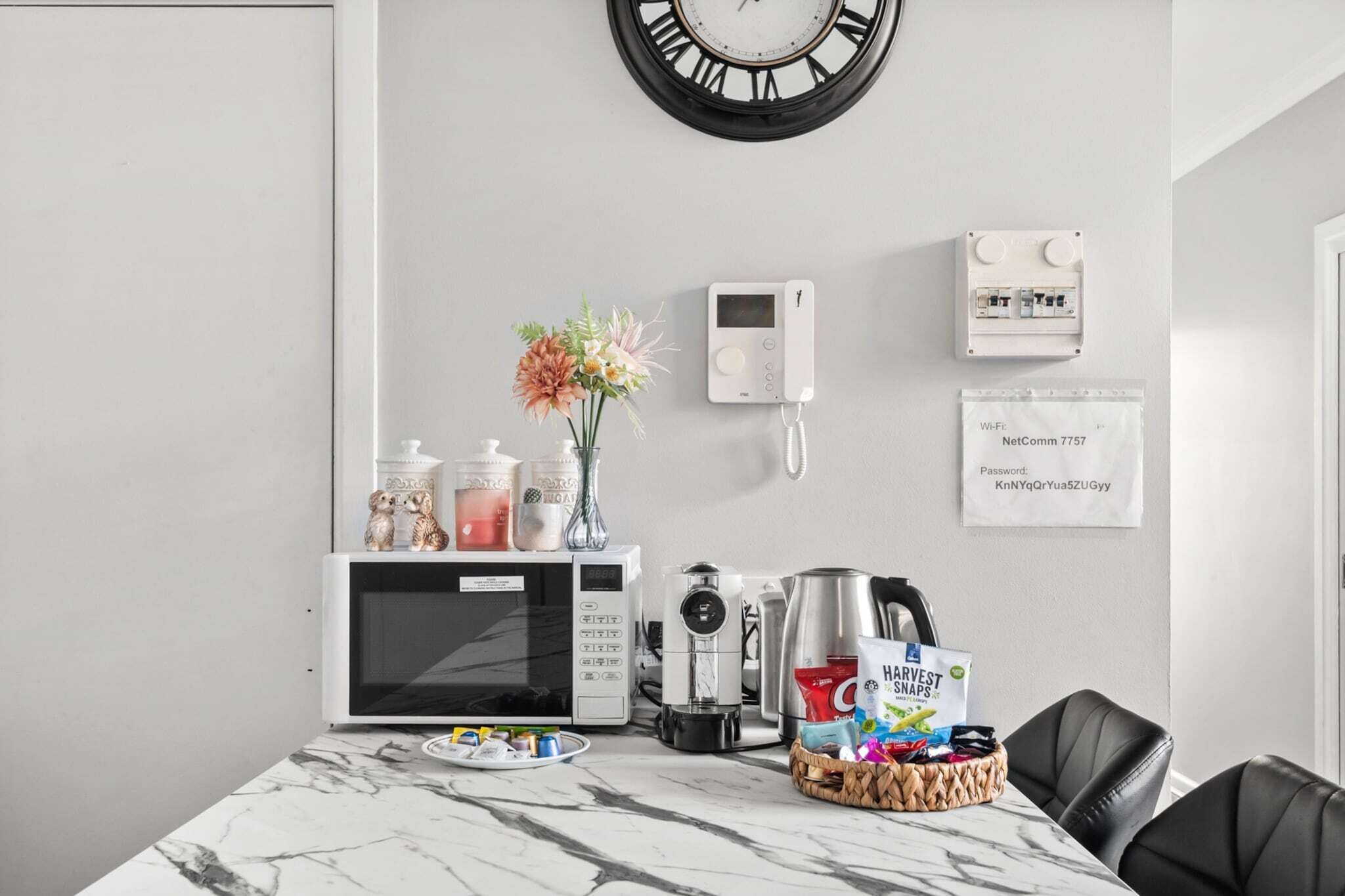 A kitchen with a microwave, coffee maker, and a basket of snacks.