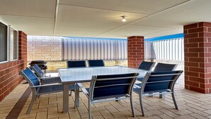 An outdoor patio area with a table and chairs, a grill, and a view of the sky through a window. - Spacious 3-Bed Home in Peaceful Byford (Byford)