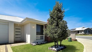 A modern single-story house with a garage, a well-maintained lawn, and a mature tree. - Spacious 3-Bed Home in Peaceful Byford (Byford)