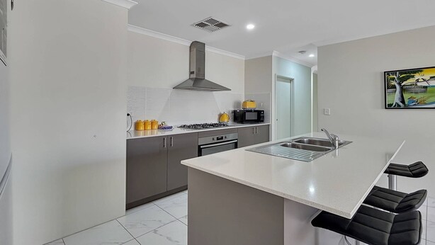 A modern kitchen with a central island, grey cabinets, a black stove, and a microwave. - Spacious 3-Bed Home in Peaceful Byford (Byford)
