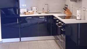 Moderni keittiö, jossa on tummat kaapit, valkoinen työtaso ja sisäänrakennettu liesi.