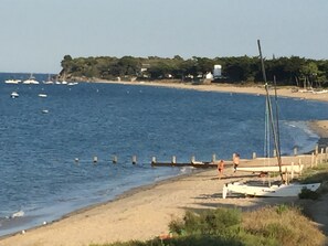 Uma praia com barcos, um cais de madeira e uma faixa de areia.