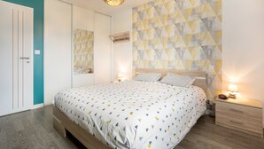 Ein Schlafzimmer mit Bett, Nachttischen, einem Kleiderschrank und einer Wand mit geometrischem Muster.