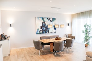 Un espace de salle à manger moderne avec une table en bois, des chaises grises et un tableau abstrait contemporain.