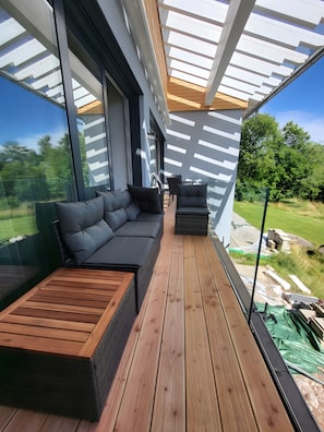 Une terrasse extérieure moderne, aménagée avec un canapé, des fauteuils et une table en bois.