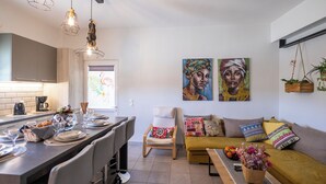 A modern kitchen with a dining area, a sofa, and two paintings on the wall. - 🏡 Paradiso Apartment | Full Air Conditioning • Outdoor Space • Near Corfu Town (Ionian Islands)
