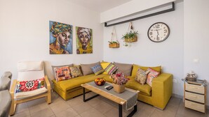 A living room with a sofa, armchair, coffee table, and a wall clock. - 🏡 Paradiso Apartment | Full Air Conditioning • Outdoor Space • Near Corfu Town (Ionian Islands)
