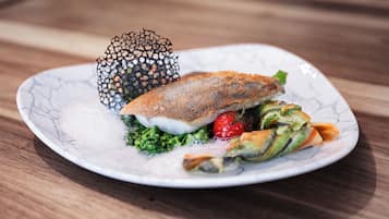 A plate with a fish sandwich, greens, and a decorative item.