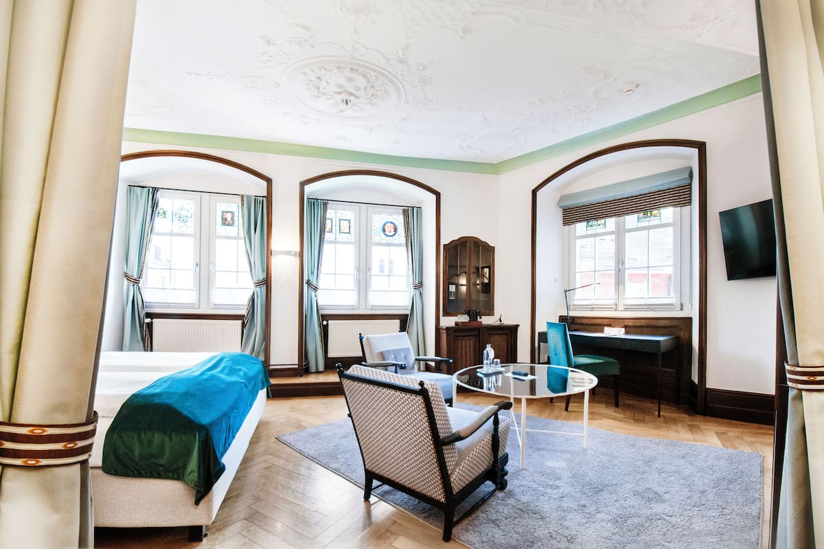 A hotel room with a bed, a desk, a chair, and a television.