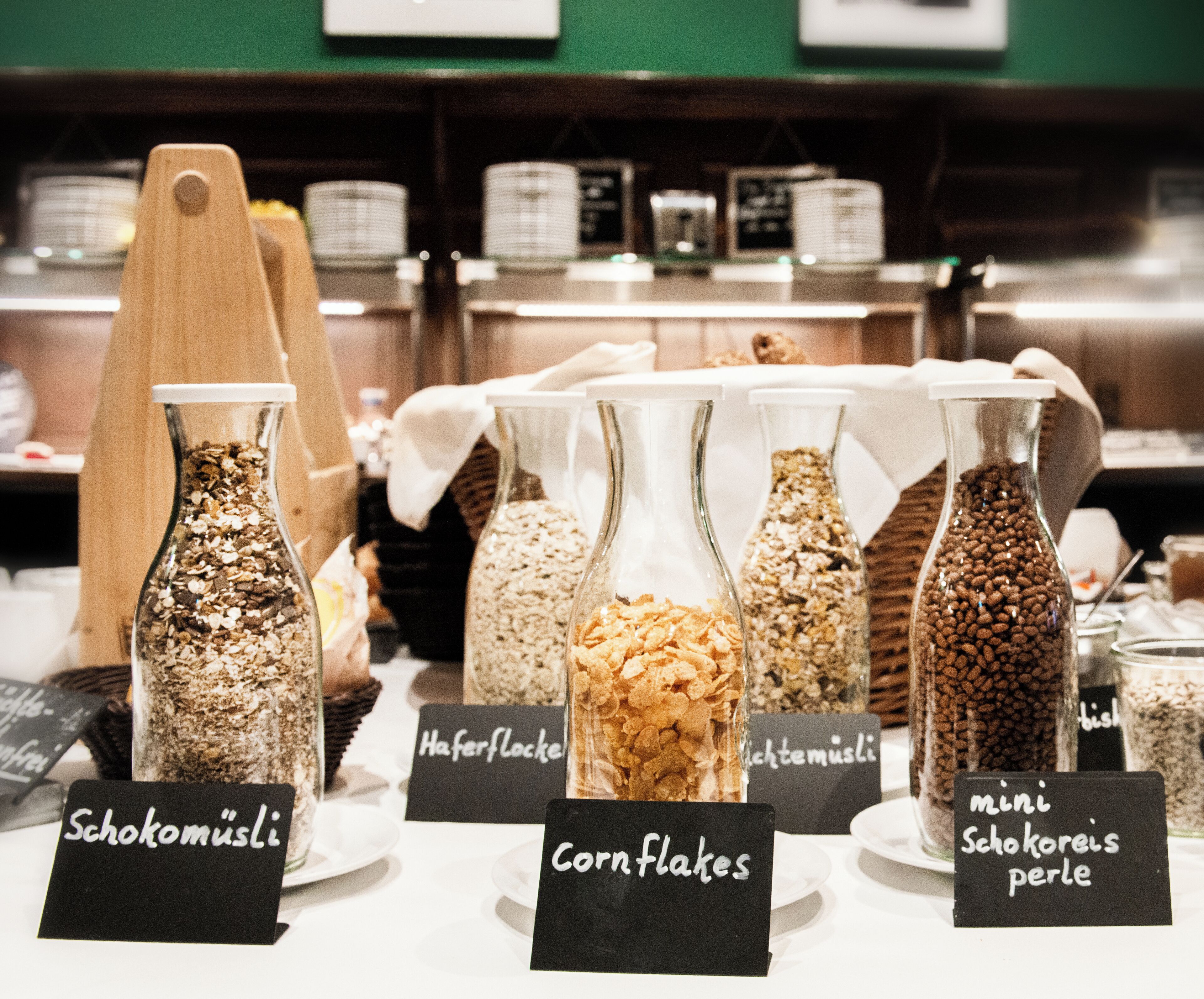 A variety of food items in glass jars with labels indicating different types of grains and flakes.