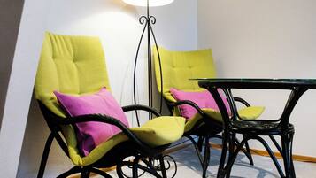 Une pièce avec deux chaises noires dotées de coussins jaunes et roses, une petite table noire et un lampadaire.