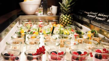 Variedad de parfait de fruta y yogur en frascos de vidrio sobre una mesa de buffet.
