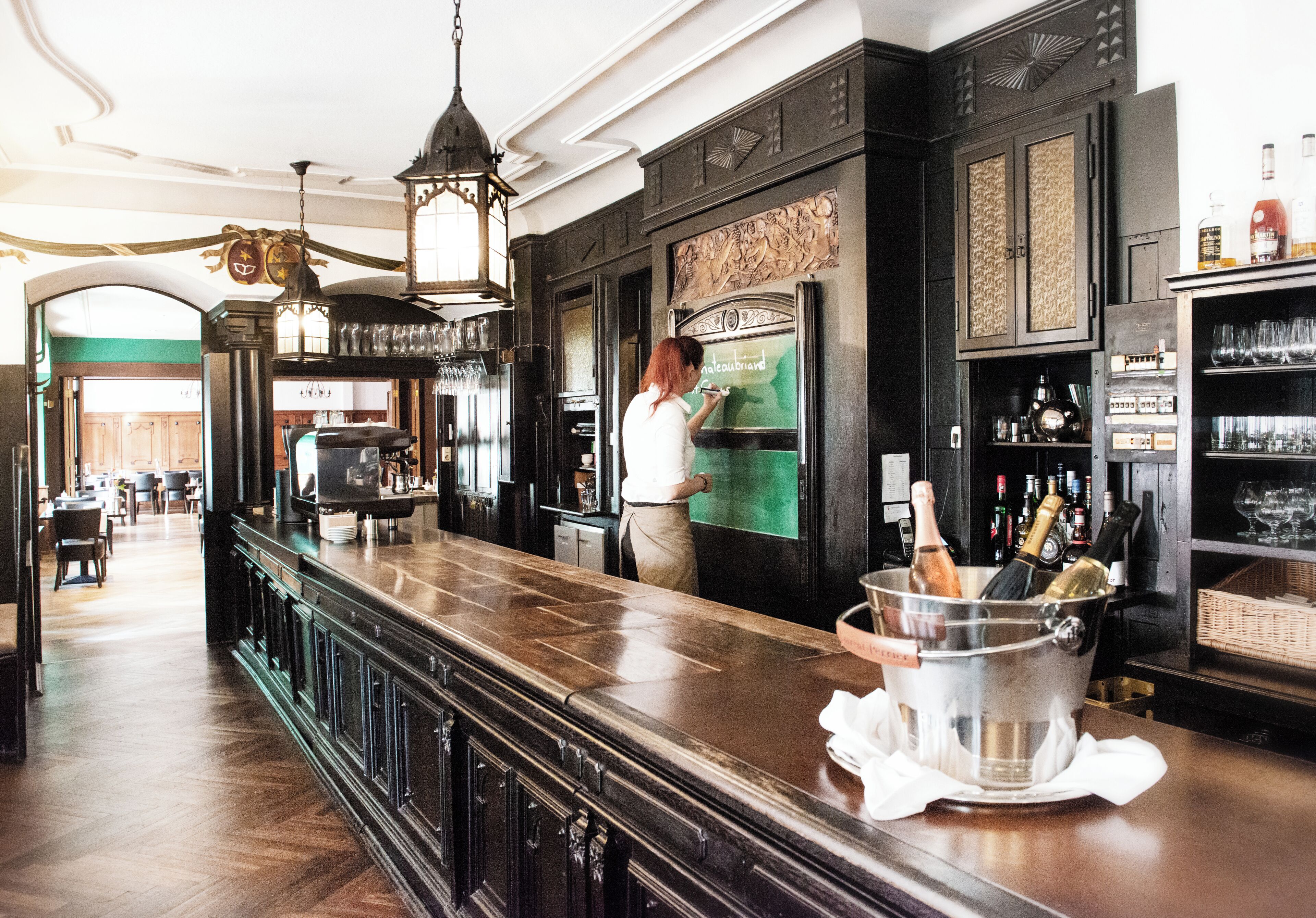 Una zona de bar con mostrador de madera, un enfriador de vinos y una botella de champán.