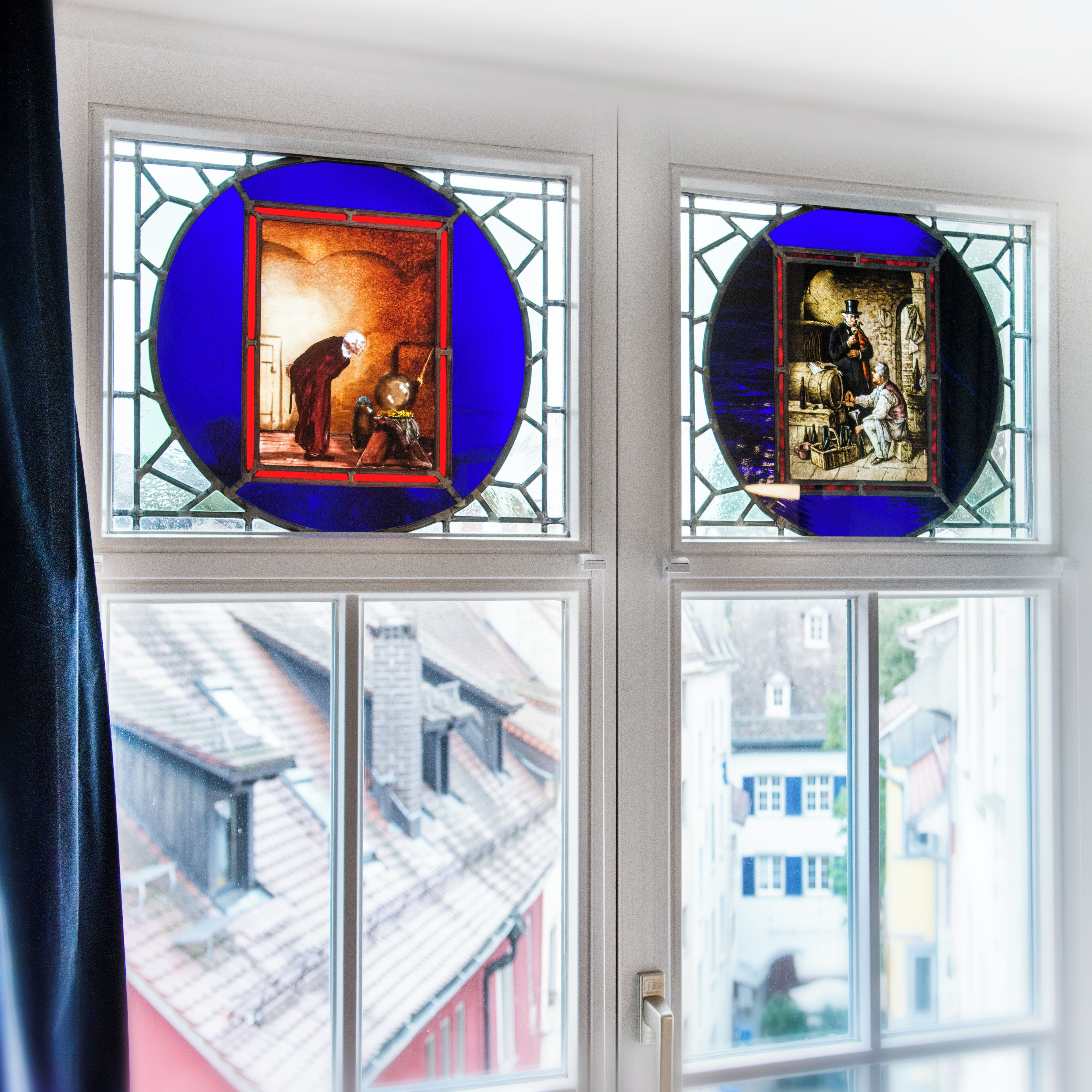 A window with two stained glass panels depicting historical scenes.