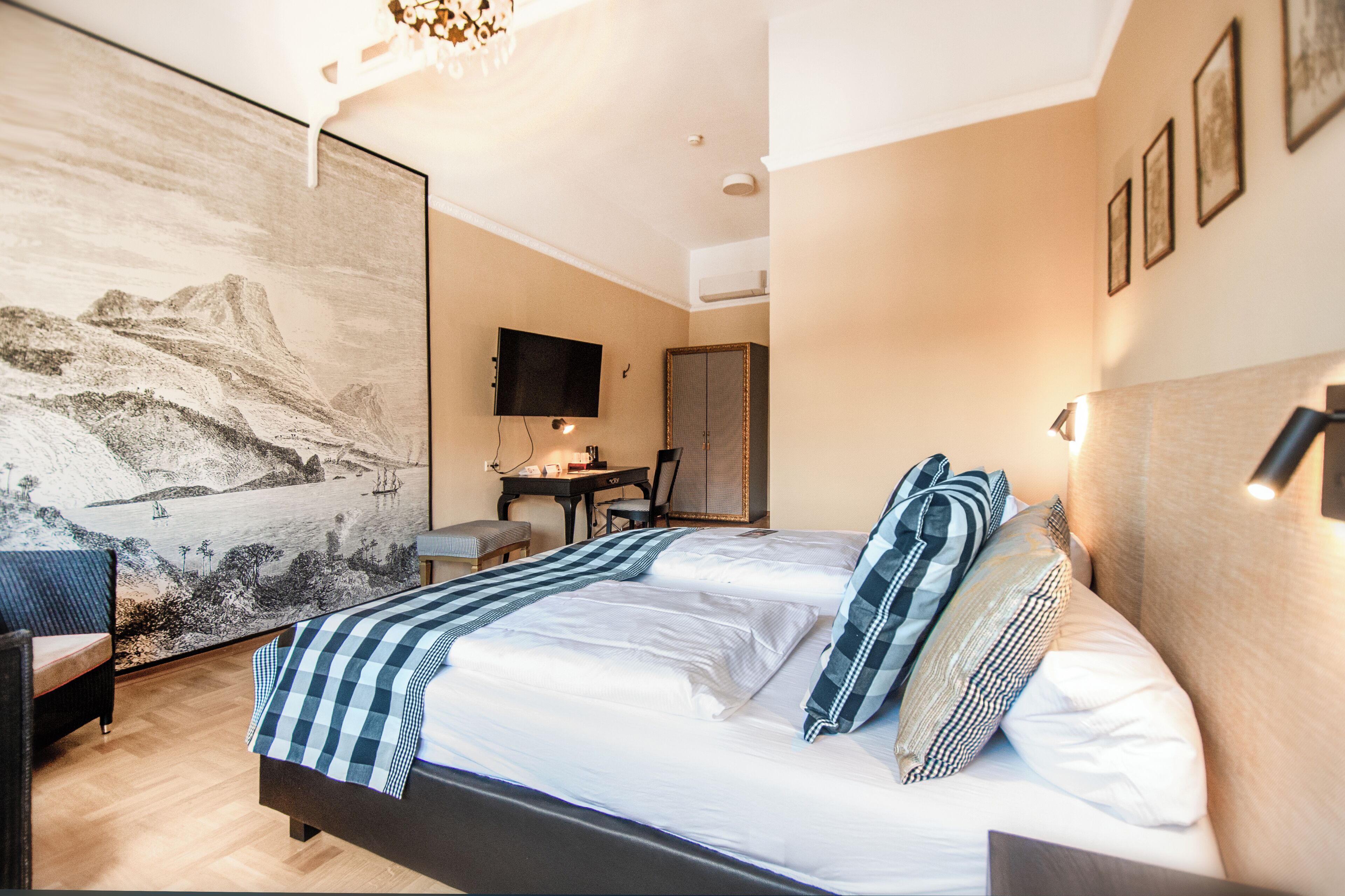 A hotel room with a bed, a desk, a chair, and a large painting on the wall.