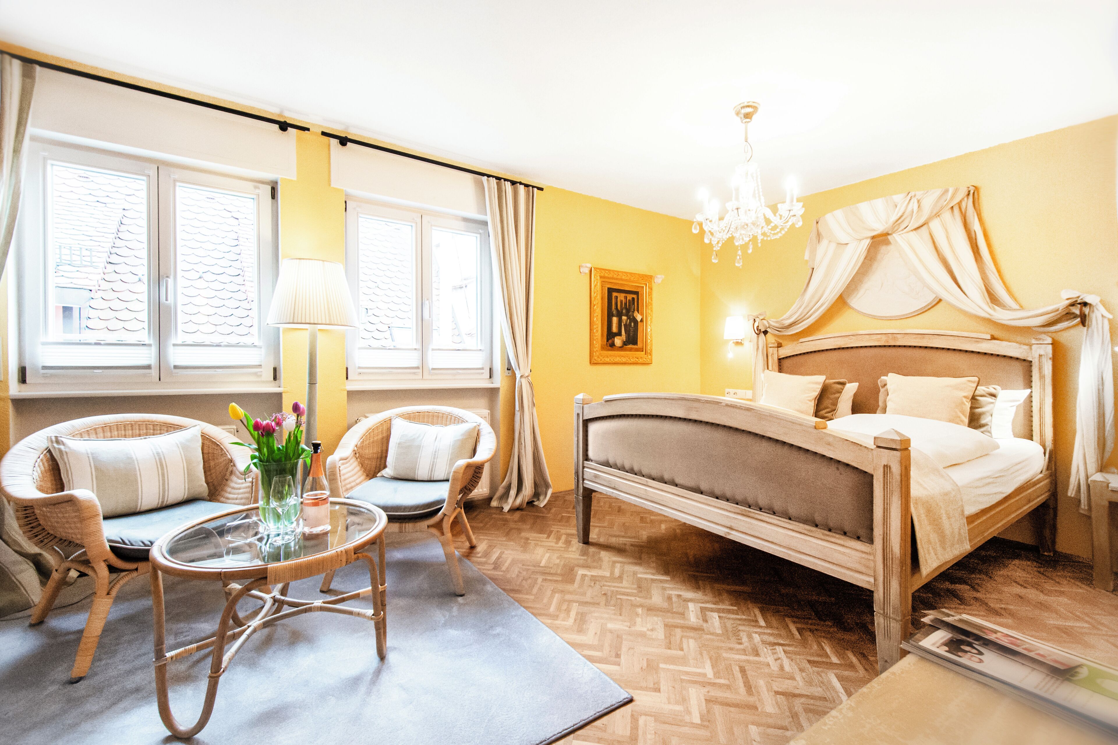 Ein Schlafzimmer mit einem Bett, zwei Stühlen, einem Tisch und einer Kristallleuchter.