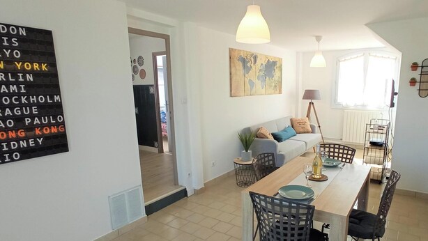 Un salon moderne avec un coin repas, une carte du monde accrochée au mur et un panneau indiquant les principales villes.
