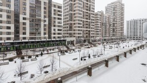 Un complejo residencial de edificios altos con varios bloques de apartamentos, una pasarela peatonal y una plaza cubierta de nieve.