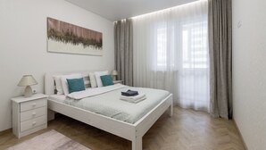 Un dormitorio moderno con cama, mesita de noche y un cuadro en la pared.