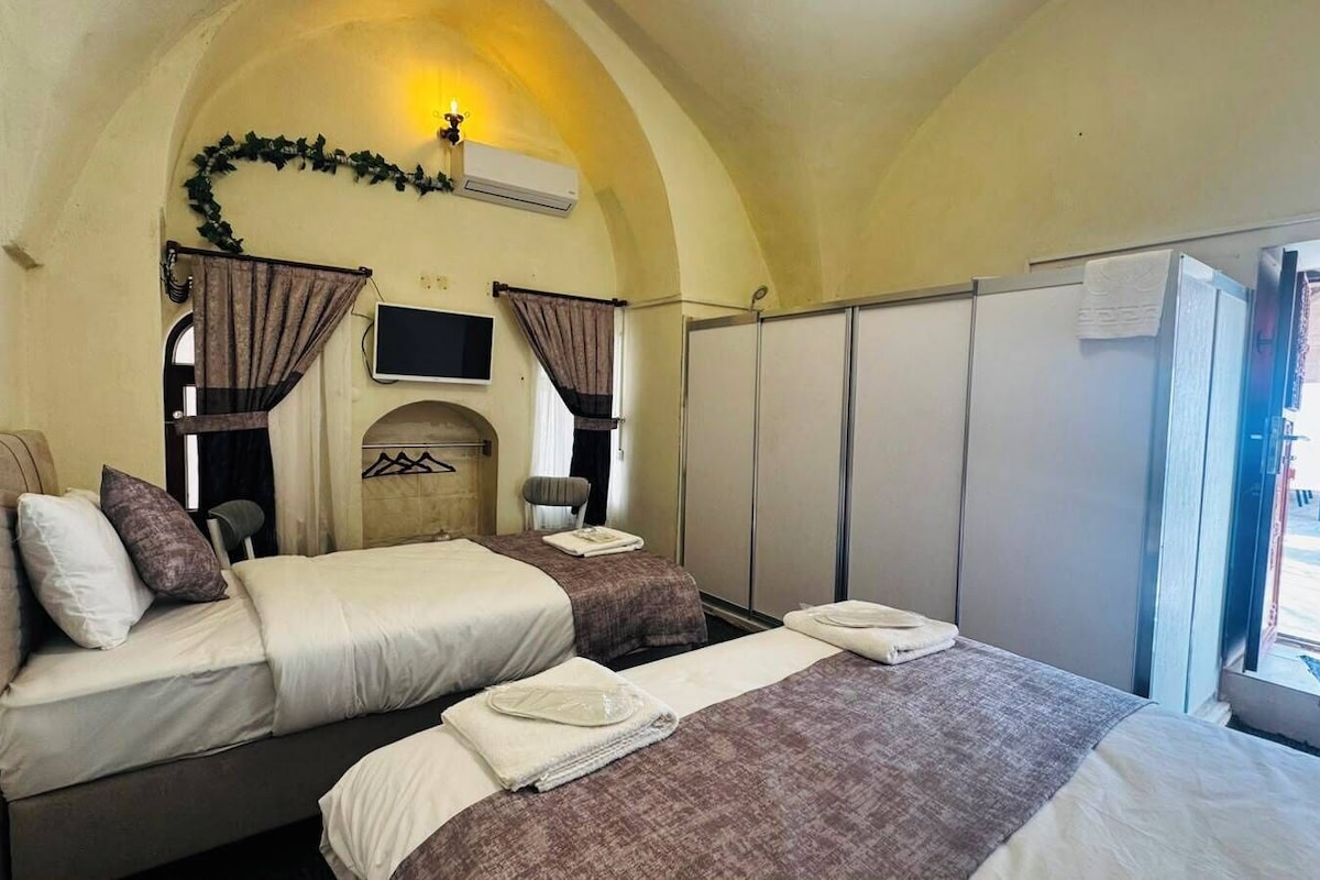 A double bed with a headboard, a bedside table, and a TV mounted on the wall.