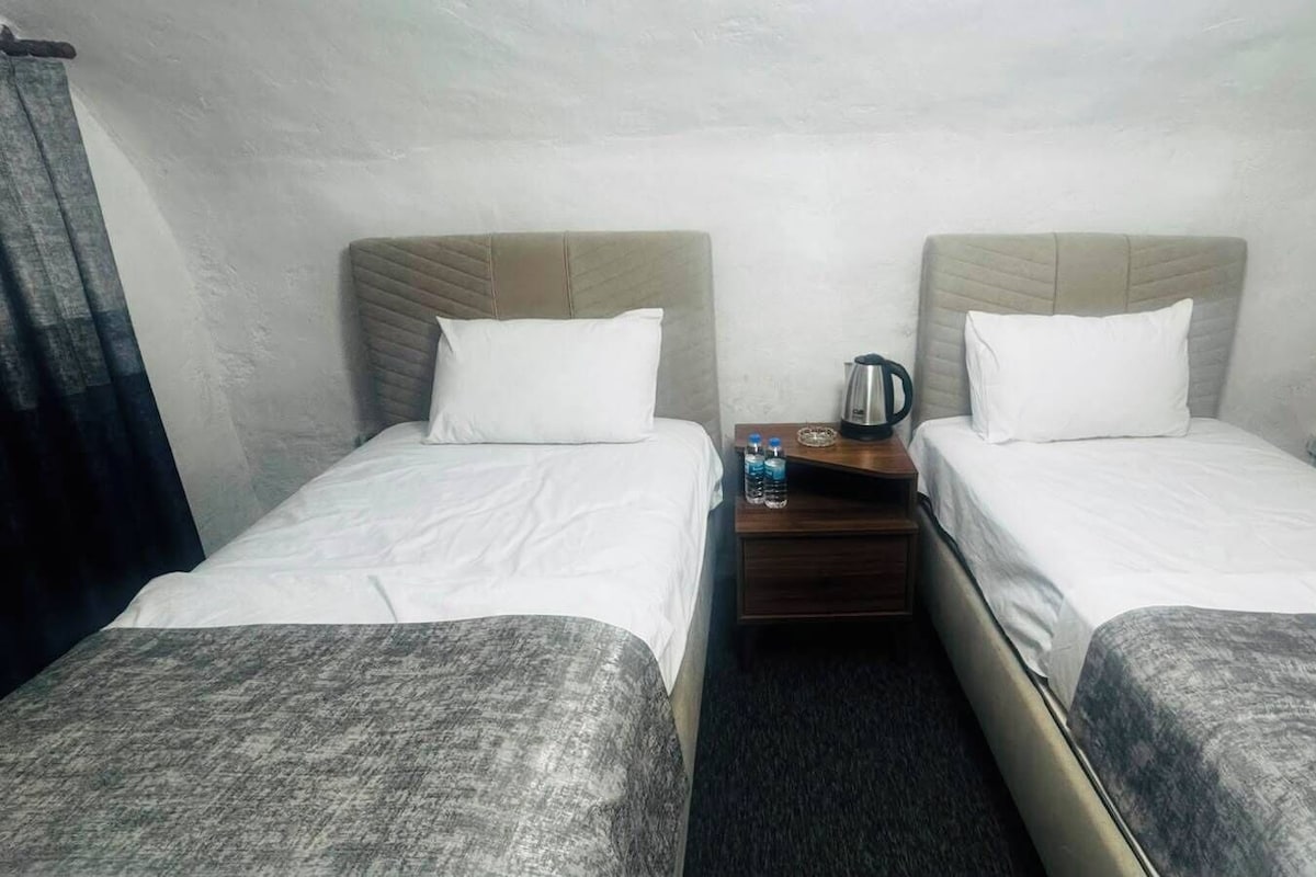 A twin room with two beds, a nightstand, and a kettle.