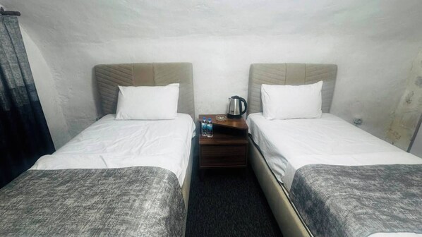 A twin room with two beds, a nightstand, and a kettle. - Tunç Paşa Konağı (Mardin)