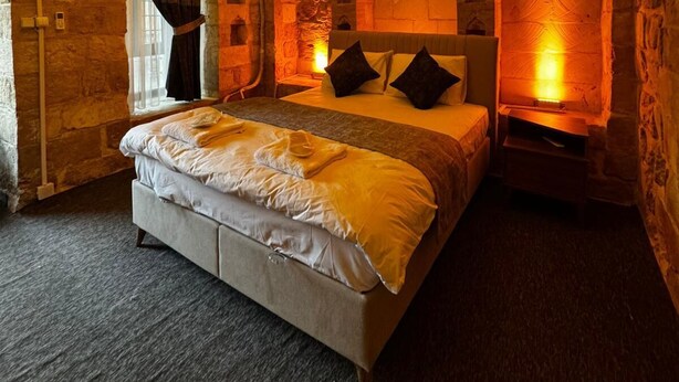 A bedroom with a stone wall, a bed, and a chandelier. - Tunç Paşa Konağı (Mardin)