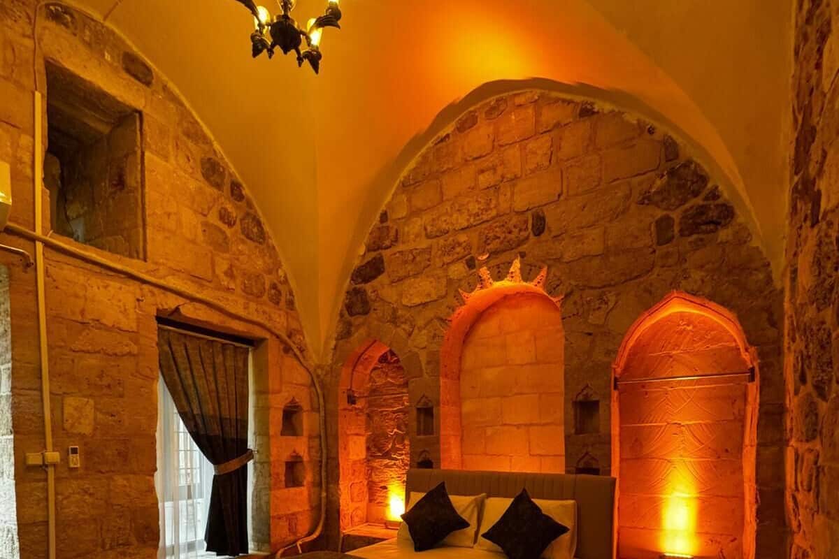 A bedroom with a stone wall, a bed, and a chandelier.