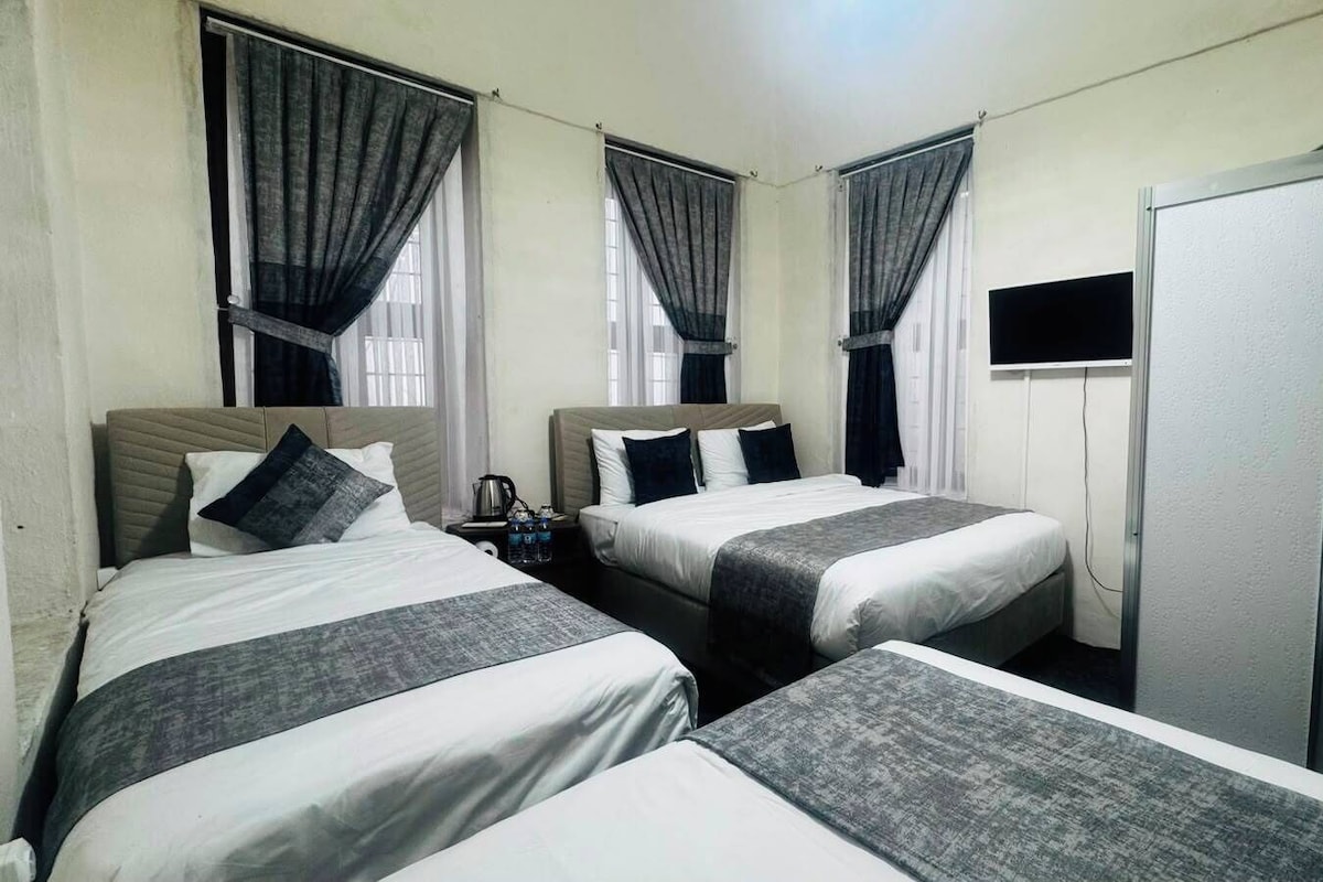 A hotel room with two beds, a TV, and a wardrobe.