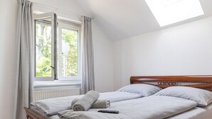 A bedroom with a wooden bed, two pillows, a remote control, and a window with curtains. - Spacious Garden Villa | 16 Guests (Vienna)