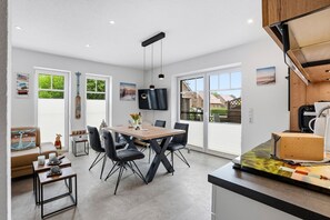Una cucina moderna con zona pranzo, ampie finestre e televisore a schermo piatto.