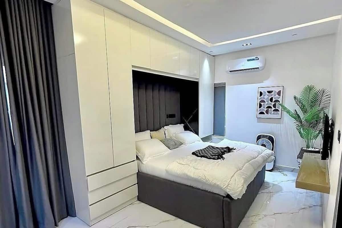 Un dormitorio moderno con una cama grande, armario empotrado y una lámpara en el techo.