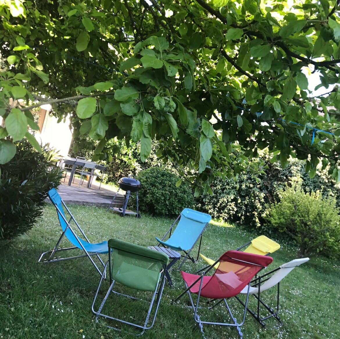A grassy outdoor area with four folding chairs in various colors.