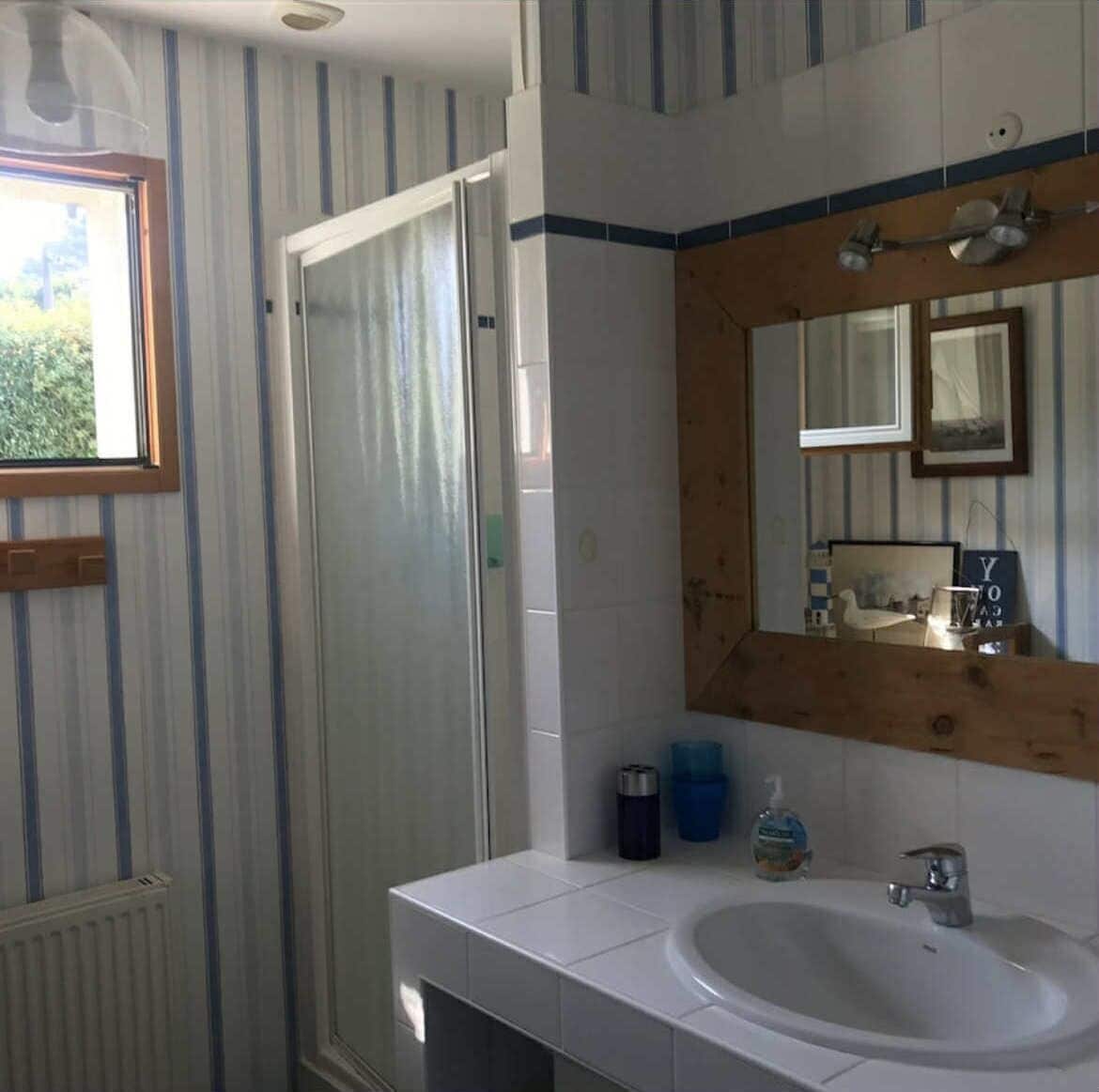 A bathroom with a white sink, a mirror, and striped wallpaper.