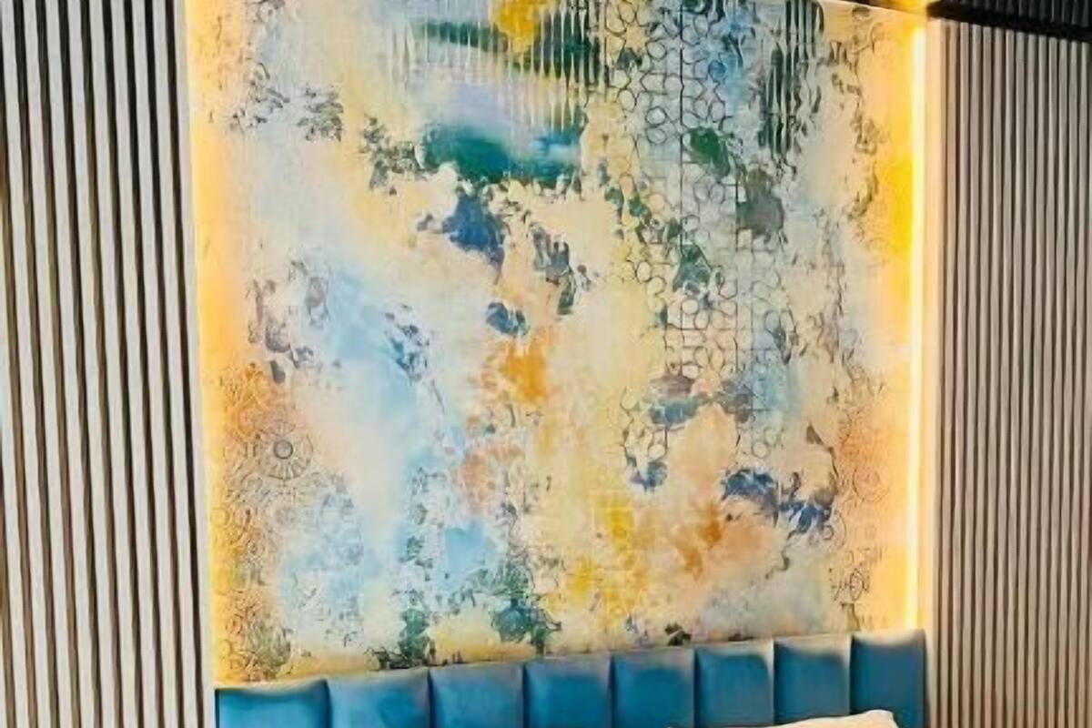 Ein modernes Schlafzimmer mit einem großen Bett, einem Kopfteil mit strukturierter Wandkunst und einem Nachttisch mit Lampe.