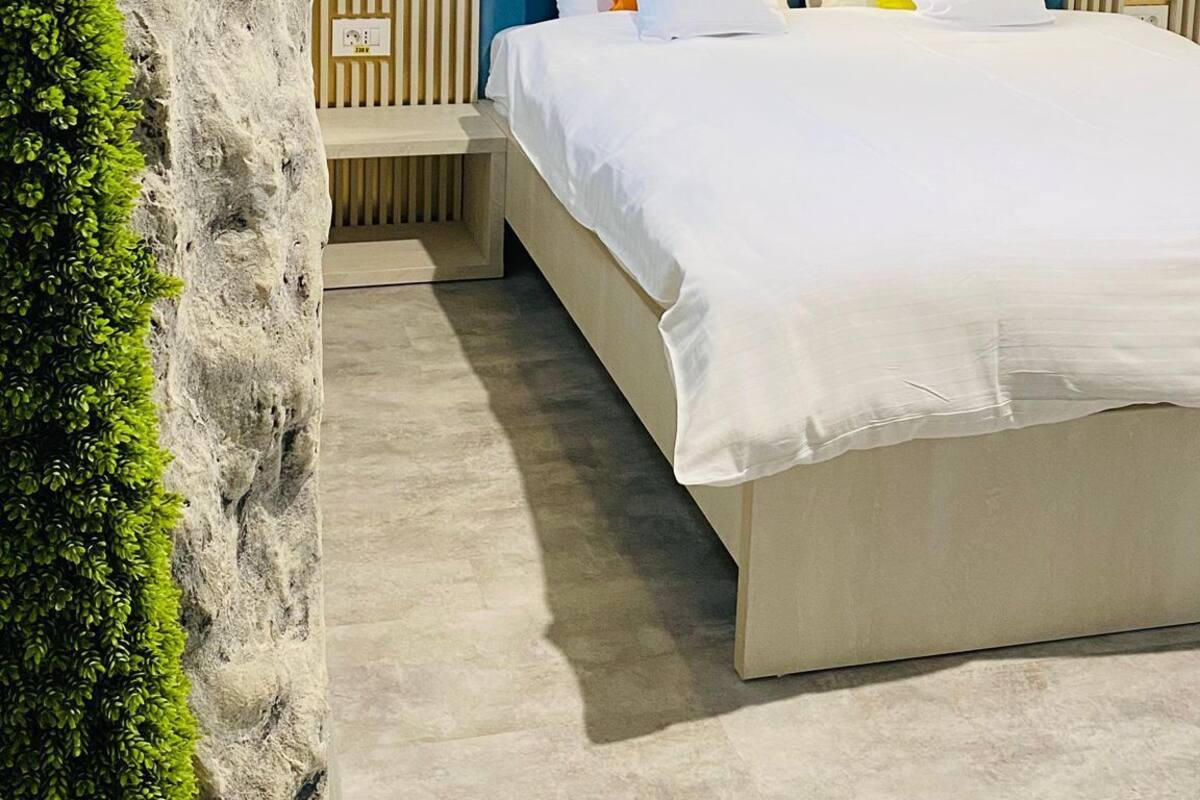Ein modernes Schlafzimmer mit einem großen Bett, einer Kopfteil mit vertikalen Linien und einer strukturierten Wand darüber.