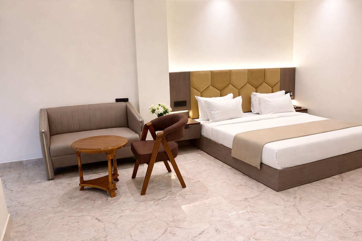 Una habitación de hotel con una cama, un sofá, una mesa de madera y una silla.