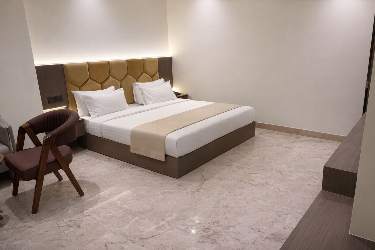 A modern hotel room with a large bed, a wooden chair, and a marble floor.