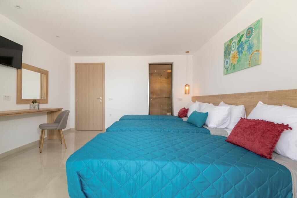 Une chambre d’hôtel avec un grand lit, un bureau, une chaise et un téléviseur.