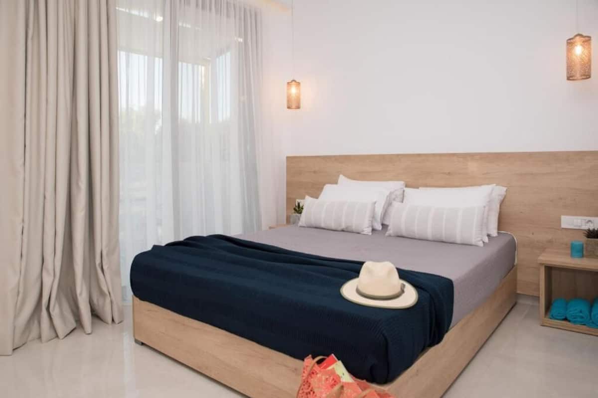 A neatly made bed with a wooden headboard, white pillows, and a dark blue blanket.
