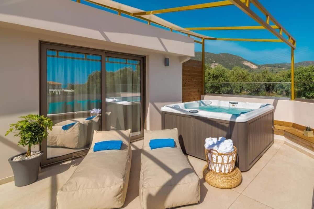 A balcony with a hot tub, two cushioned seating areas, a potted plant, and a wicker basket.