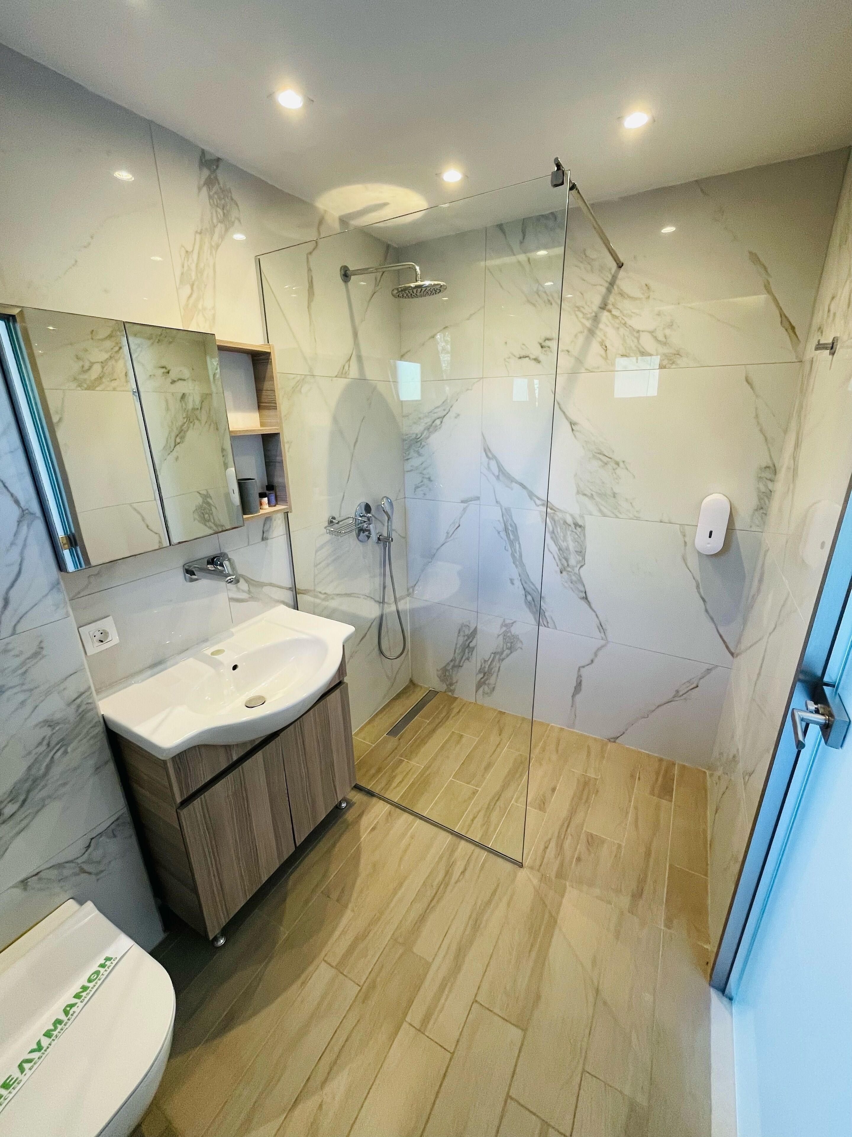 Ein modernes Badezimmer mit einer Marmerdusche, einem Waschbecken und einer Toilette.