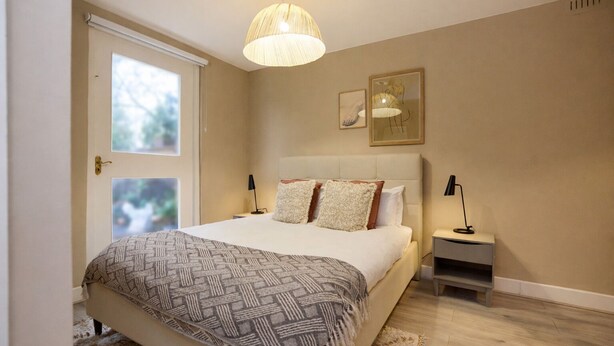 Een slaapkamer met een bed, nachtkastjes, een hanglamp en kunst aan de muur.