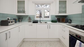 Een moderne keuken met witte kastjes, een roestvrijstalen spoelbak, een magnetron en een gasfornuis.