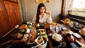 Una mesa de comedor con varios platos, un cuadro y vistas al exterior.
